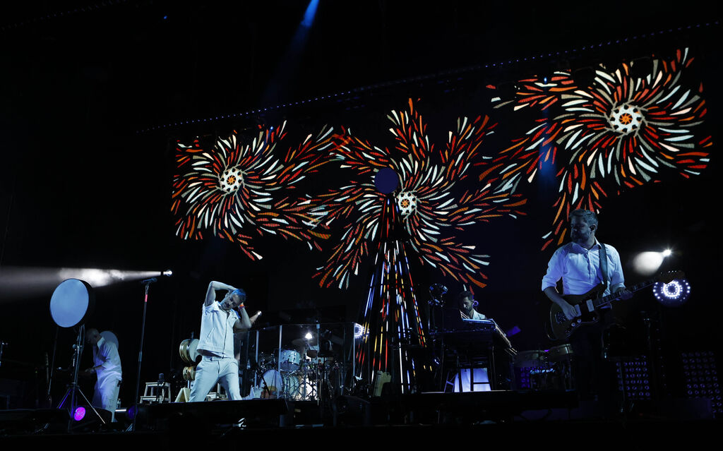 Fotos del concierto de vetusta morla en sevilla, donde se puede apreciar el fondo de proyecciones audiovisuales basadas en la estética de "cable a tierra", con formas de colores que giran entre ellas y recuerdan a los fuegos artificiales.